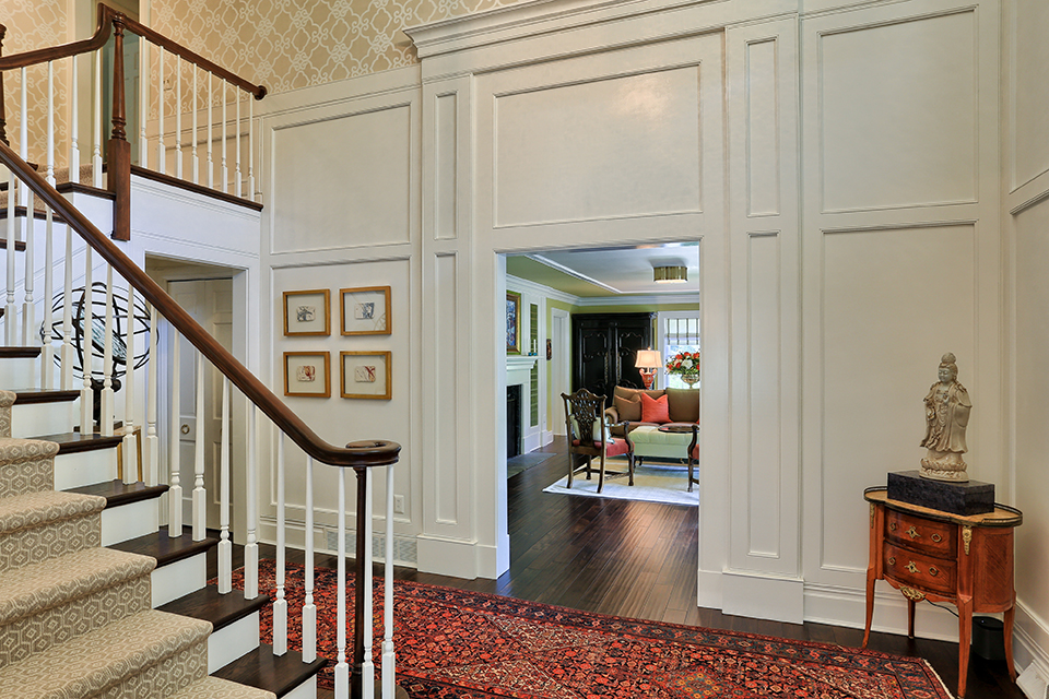 Entry way with detailed wall trim, stairway with a runner and traditional feel.