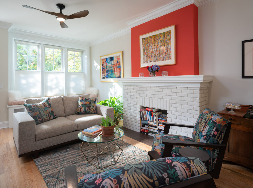 Photo of a living room with a brick fireplace, and colorful paint above the mantel.