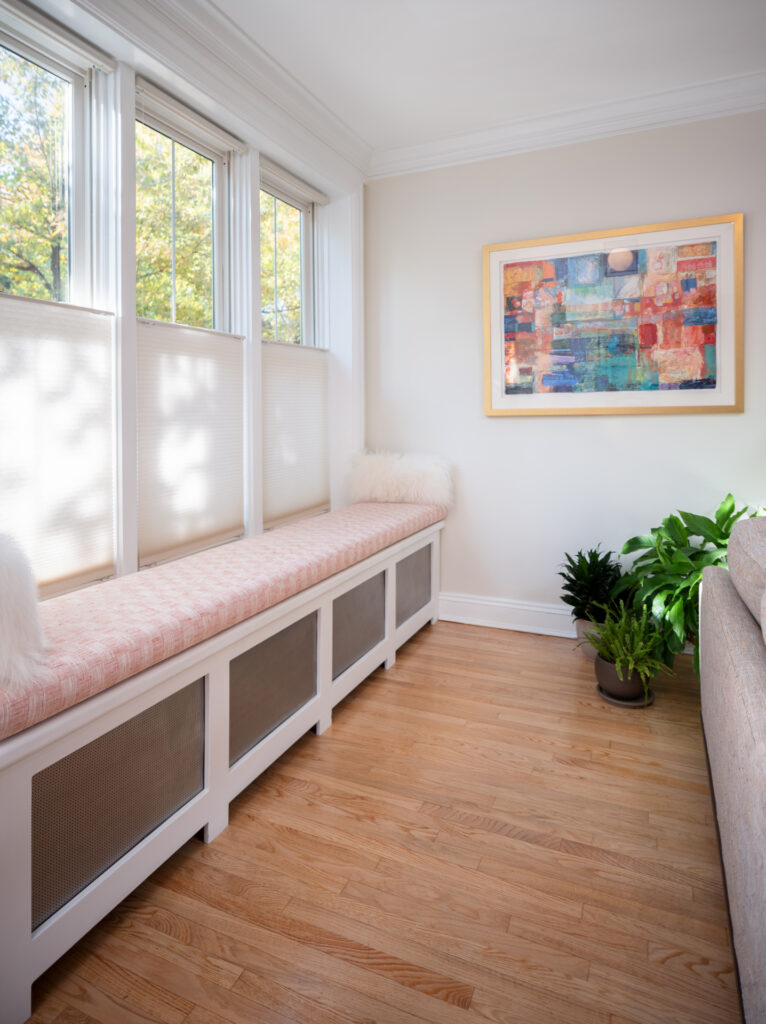 Bench seating under windows with beautiful abstract artwork and plants.