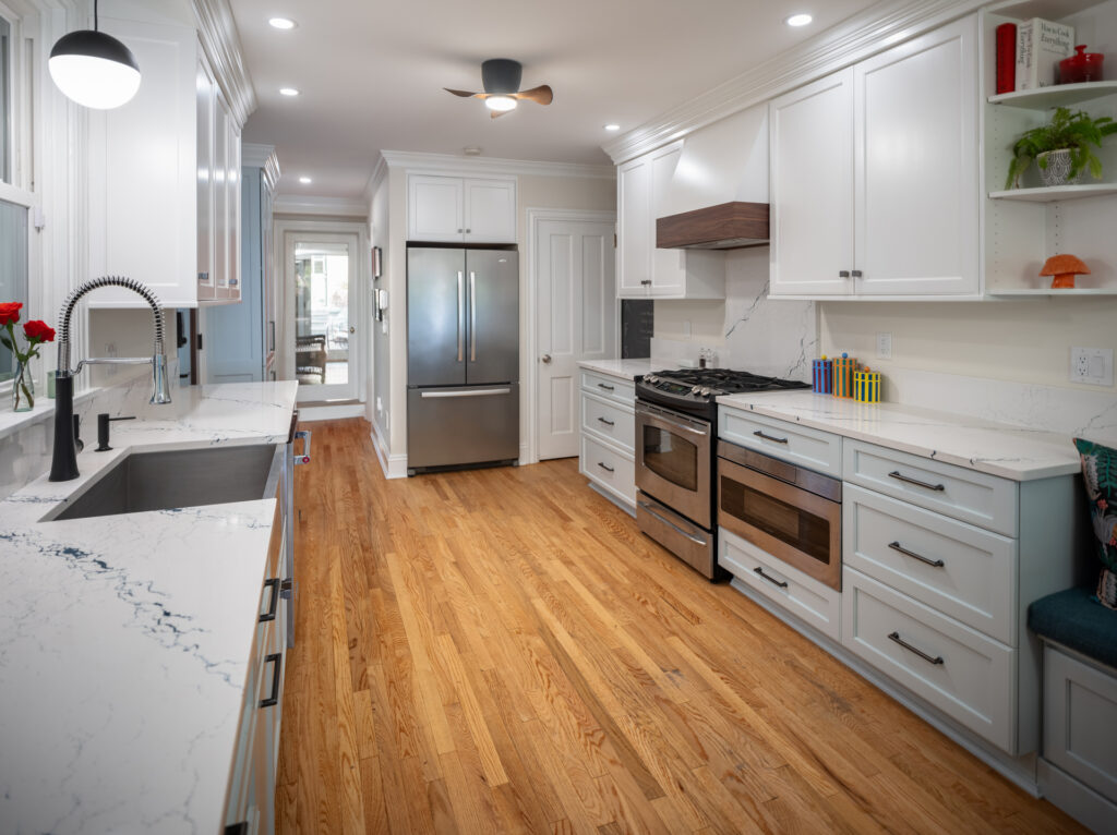 Two-tone cabinet in kitchen with stainless steel appliances, light-colored hardwood floors, and lots of light.
