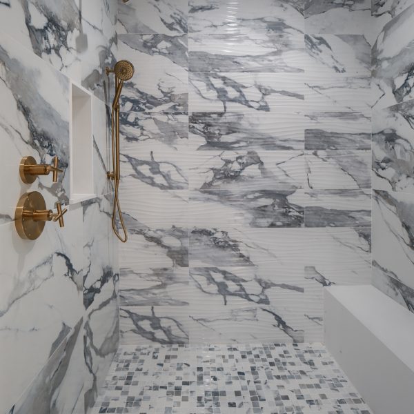 picture of a walk-in shower with bench and gold accents