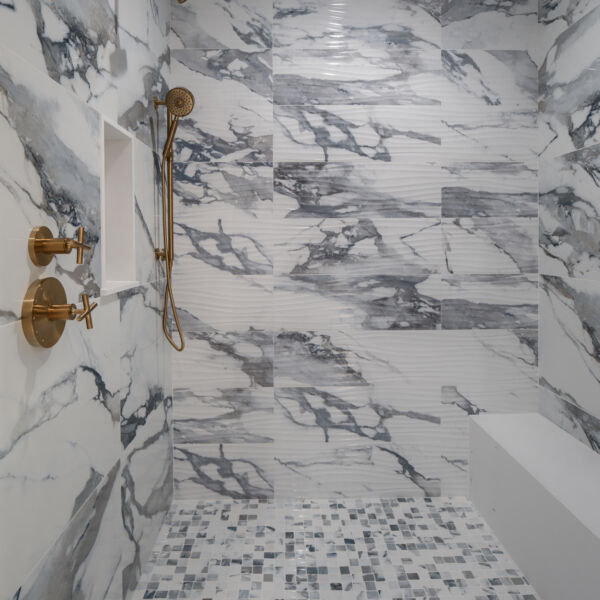 picture of a walk-in shower with bench and gold accents