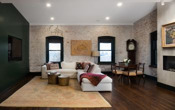 modern furniture and design in industrial warehouse penthouse, white couch, whitewashed brick wall, dark trim, dark green tv wall