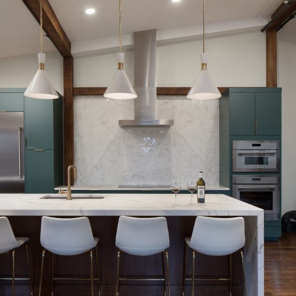 versatile kitchen island with bar seating, storage, waterfall edge white marble countertop, sage green custom cabinets, simple pendants, industrial warehouse elements