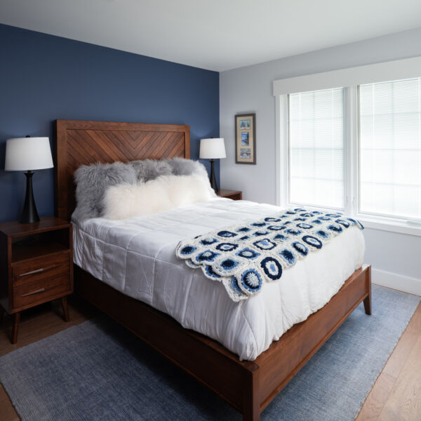 Custom wooden bed frame with navy blue walls and light blue carpet.