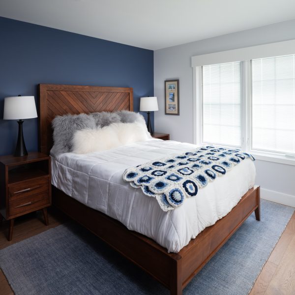 Custom wooden bed frame with navy blue walls and light blue carpet.