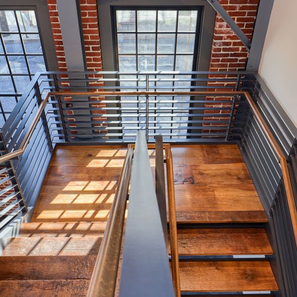 Wooden stairway against a brick wall with windows